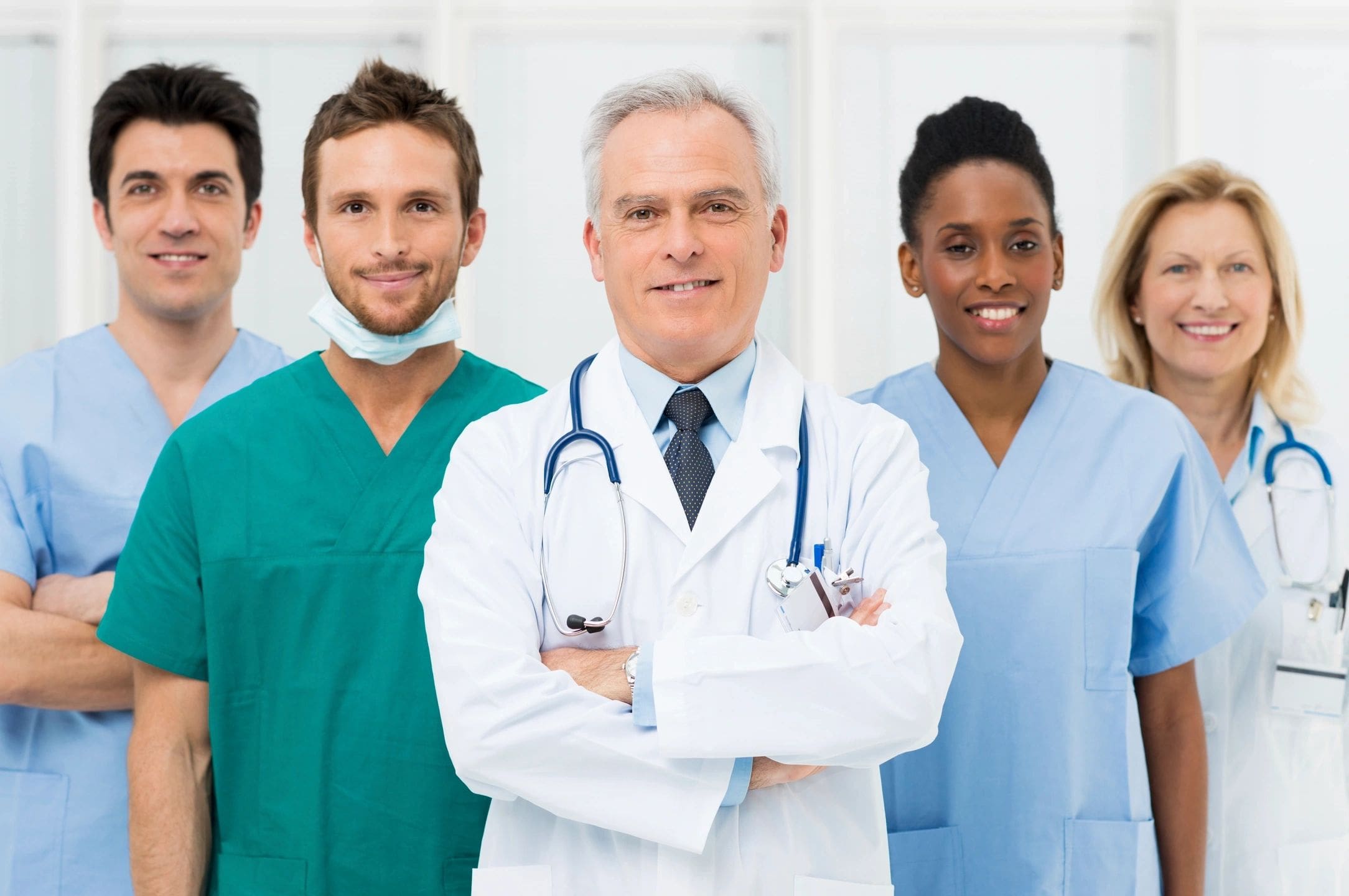 Smiling medical team in scrubs and white coat