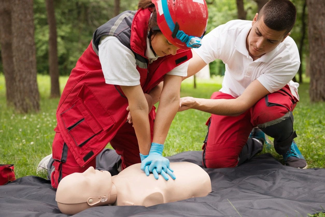 Rescuers practicing CPR on training mannequin outdoors